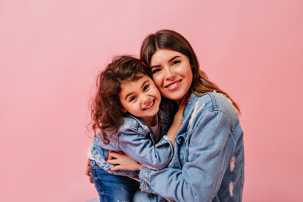 Laughing mother daughter looking camera front view young woman with preteen child isolated pink background 2